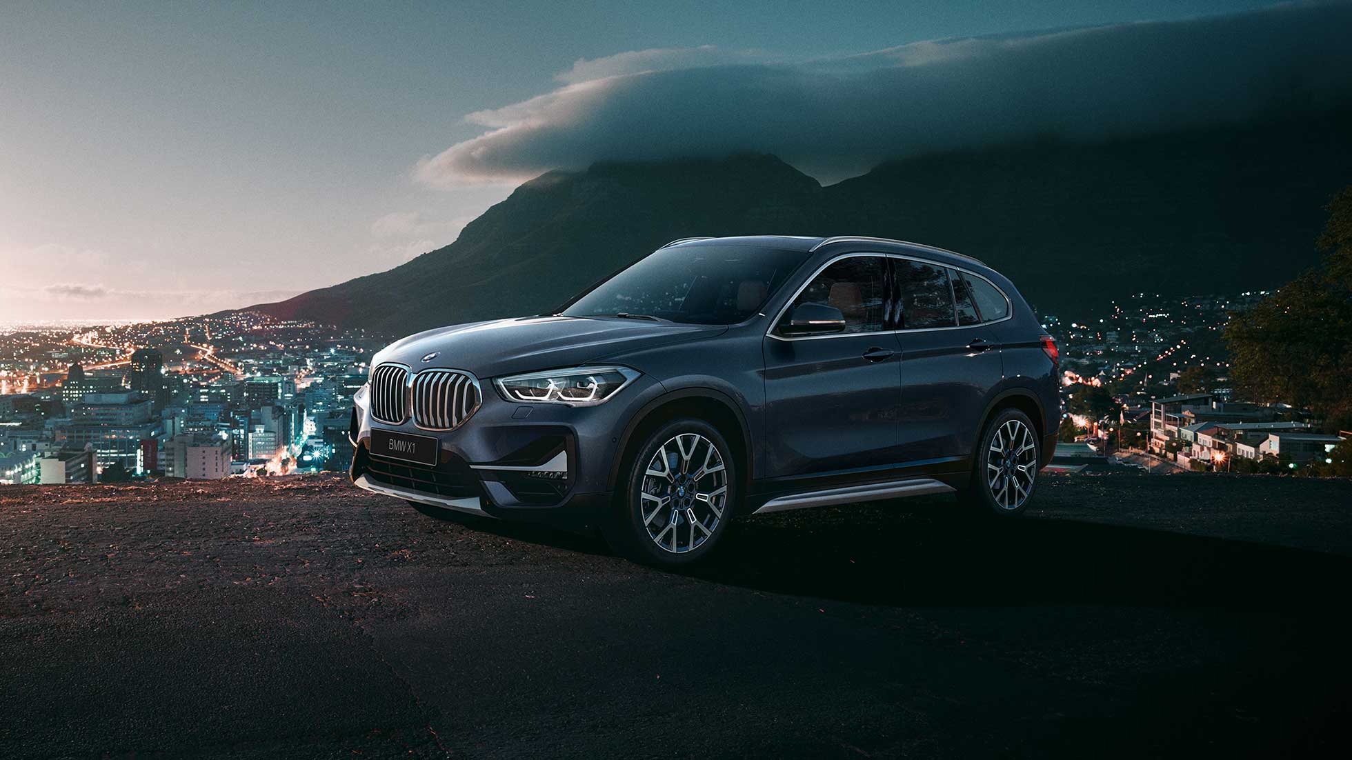 BMW X1, вид сбоку с поворотом в три четверти. BMW X1, вид сбоку с поворотом в три четверти на фоне городского пейзажа.