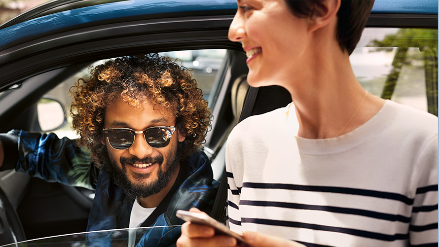 BMW Connected Мужчина и женщина сидят на диване и используют BMW, подключенные к их смартфонам