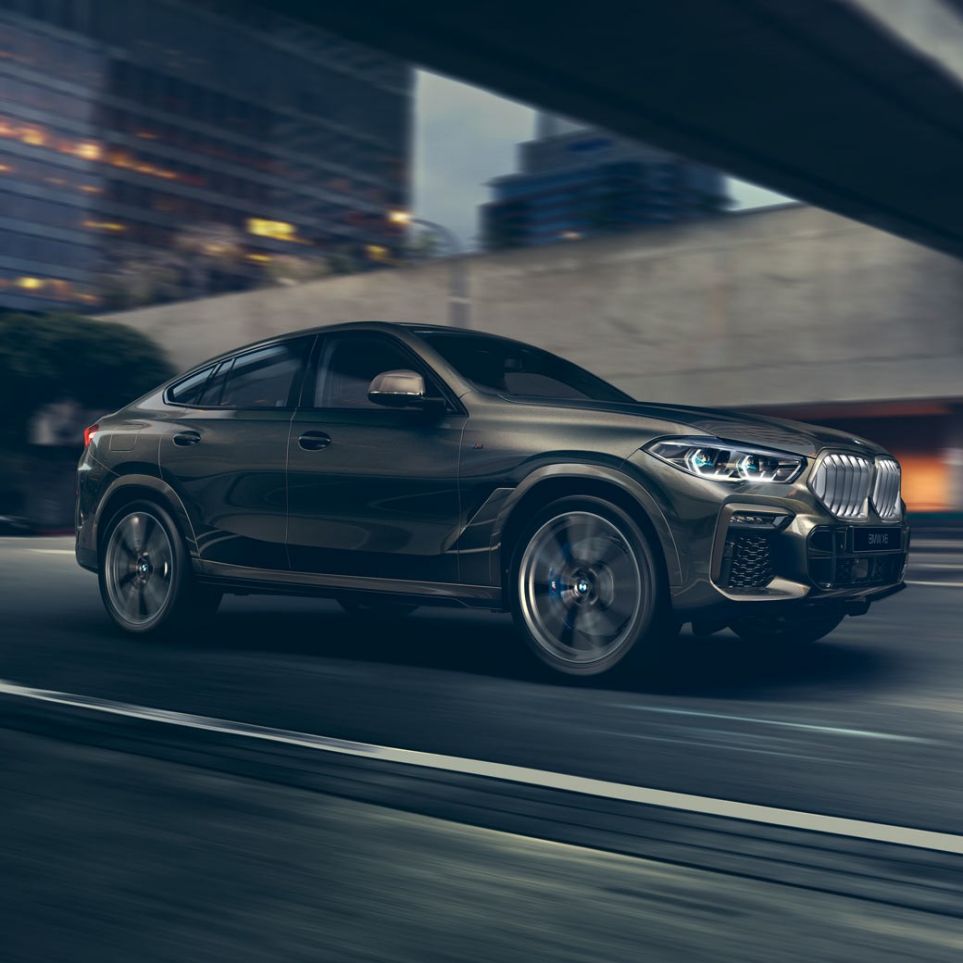 BMW X6 в движении BMW X6 в движении, вид спереди с поворотом в три четверти на фоне города